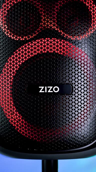 Close-up of the black ZIZO Tune Z5 party speaker's perforated grille glowing red, the ZIZO wordmark badge centered on the mesh
