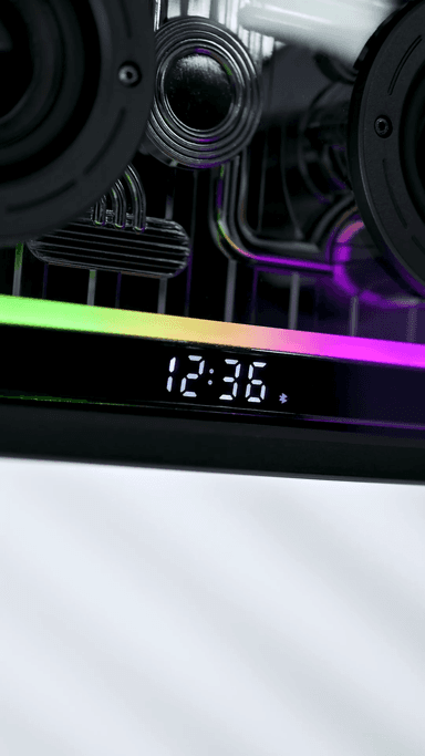 The Retro Crystal speaker's LED display reading 12:36, the RGB bar lit rainbow beneath it and the drivers visible behind the clear panel