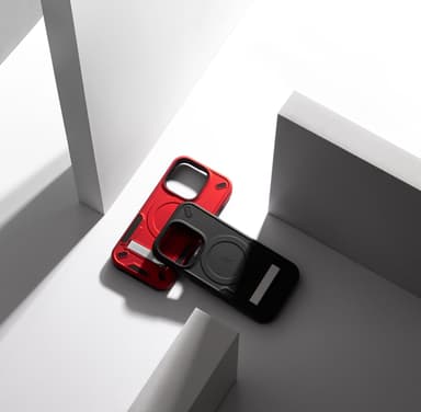 Red and black ZIZO Transform cases leaning together on angular white and gray studio blocks, kickstand tab flipped open and the MagSafe ring visible