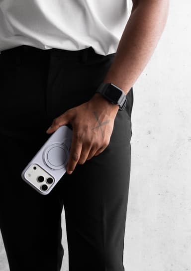 A person in a white tee and black trousers holding a translucent smoke ZIZO Revolve case at their hip