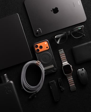 A black ZIZO Transform case with an orange camera plate laid into an all-black everyday-carry flat lay with an iPad Pro, watch and wallet