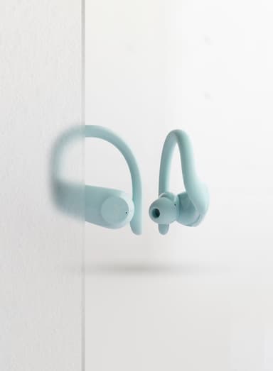 ZIZO Encore Sport Active Wireless Earbuds in Ice Blue floating beside a translucent glass panel