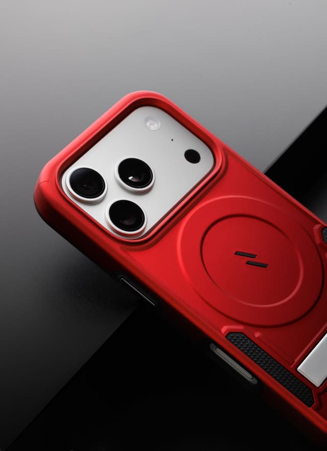 Macro angle on the camera housing of a red ZIZO Transform case, its triple-lens cutout and MagSafe ring filling the frame