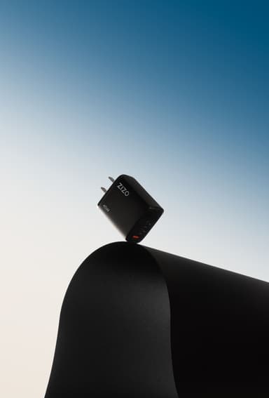 A black ZIZO PowerVault 45W wall charger balanced on a black pedestal against a blue gradient sky