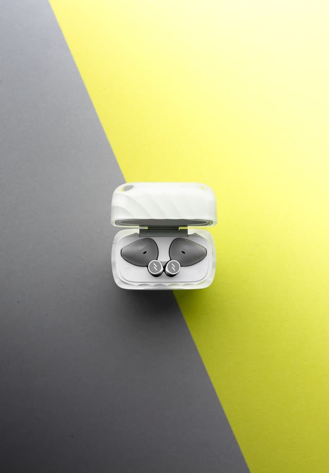 An open frosted ZIZO Halos case showing both earbuds, on a split yellow and charcoal background