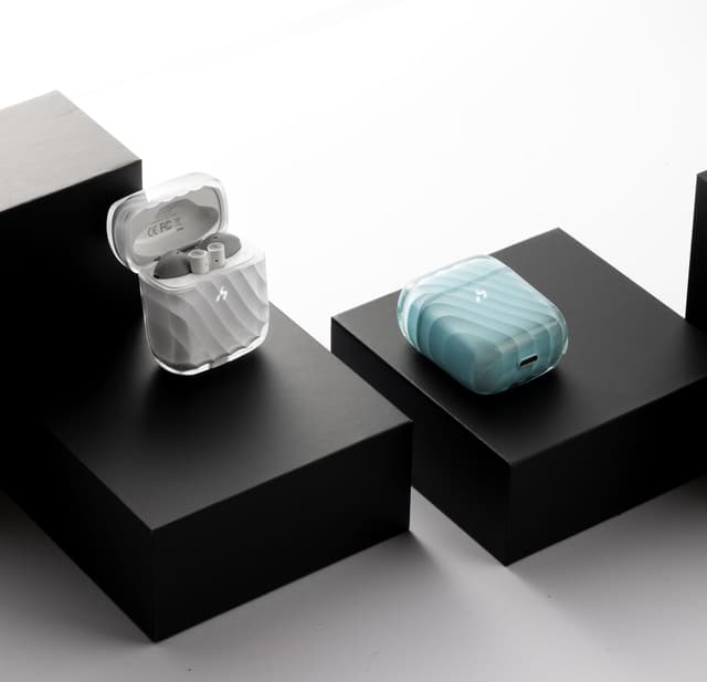 Two ZIZO Halos charging cases, one frosted clear and one pale blue, staged on black plinths