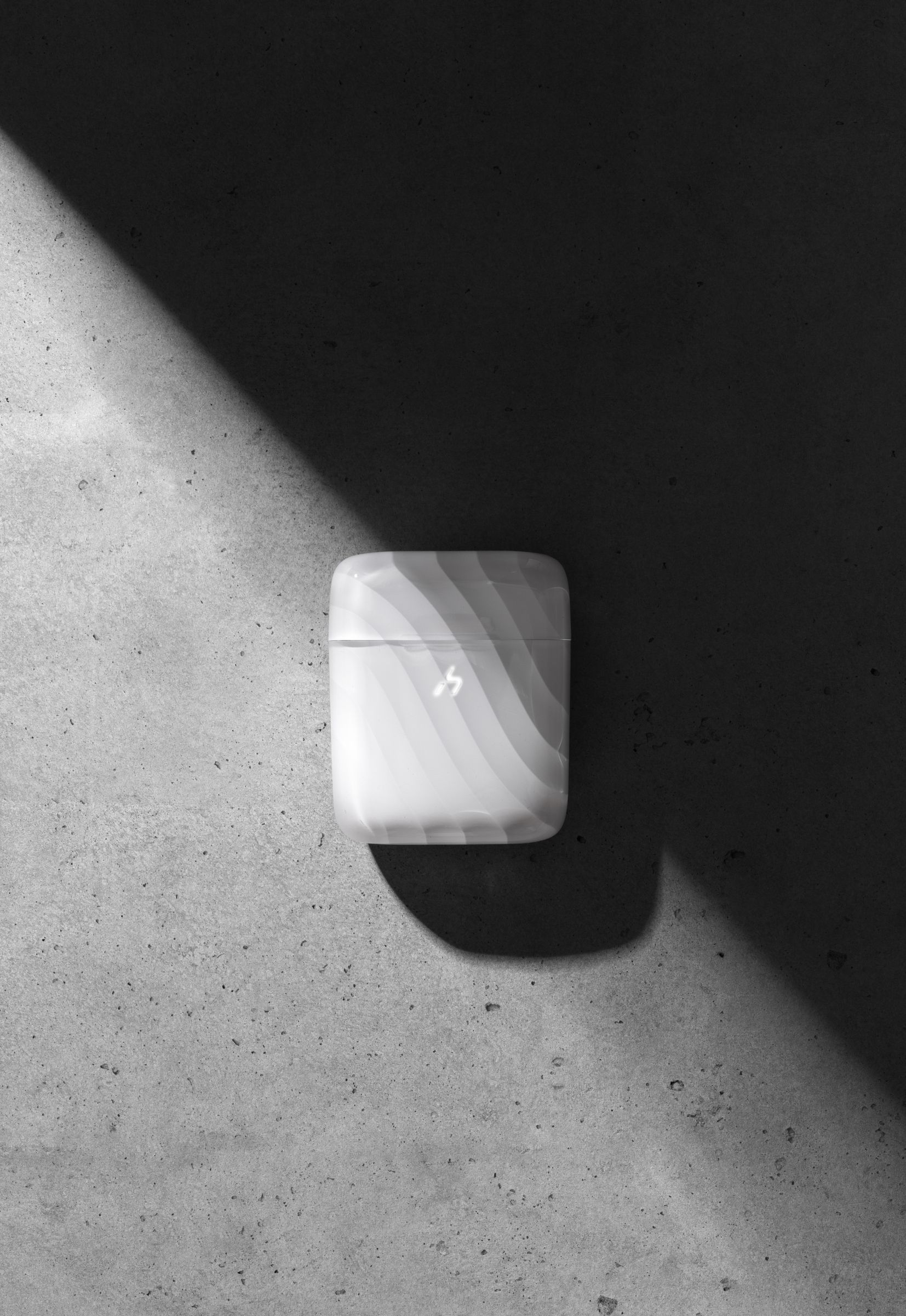 A closed frosted-white ZIZO Halos charging case on dark concrete