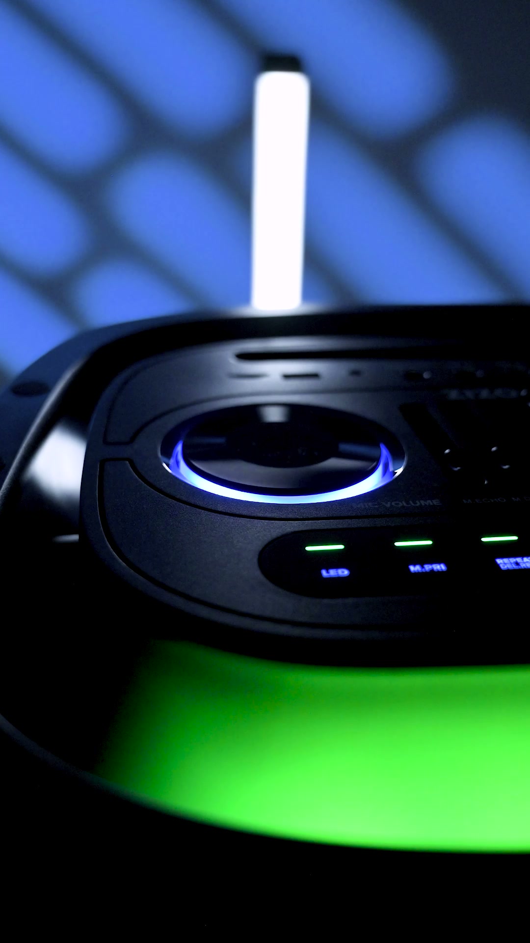 The ZIZO Boom speaker's control panel glowing blue and green in a dark room, a jog wheel and buttons lit