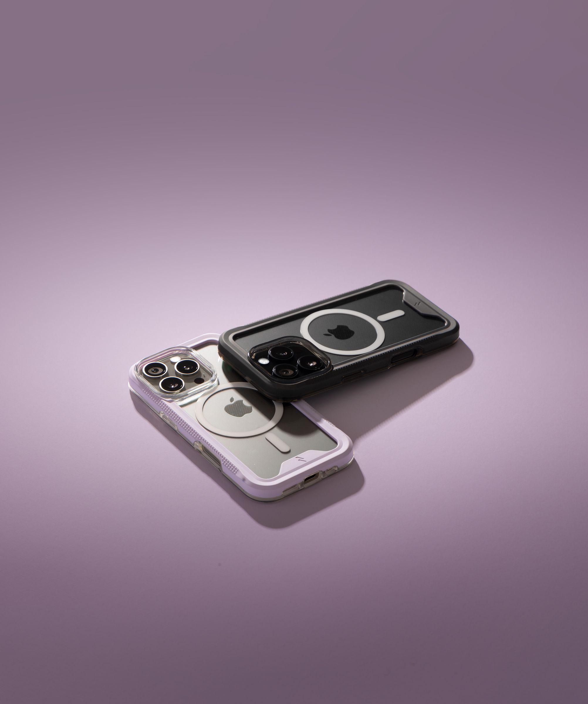 A purple-bumper ZIZO ION MagSafe case overlapping a black-bumper one on a soft purple gradient background