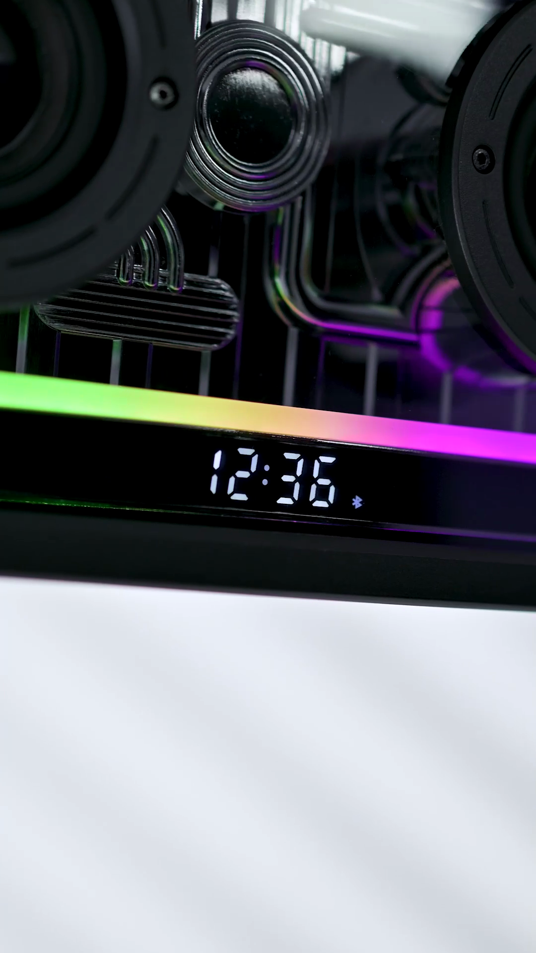 The Retro Crystal speaker's LED display reading 12:36, the RGB bar lit rainbow beneath it and the drivers visible behind the clear panel