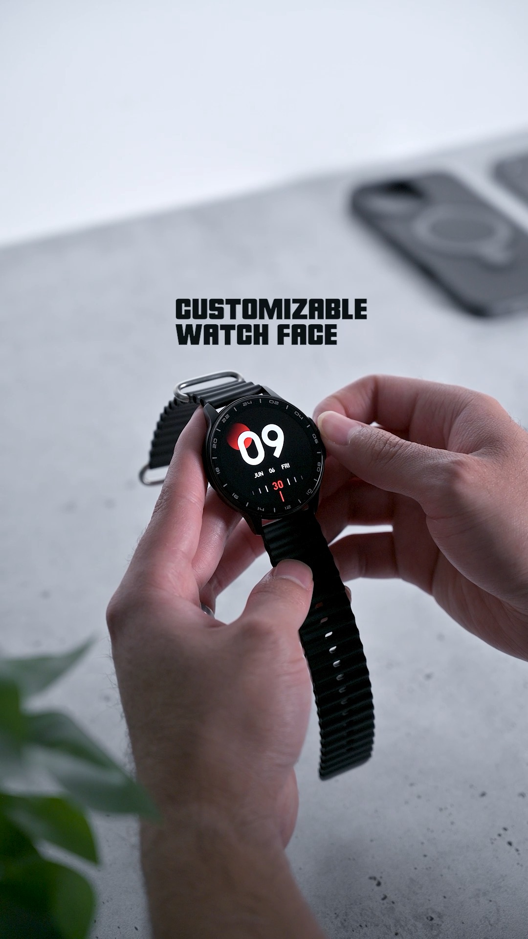 Two hands adjusting the ZIZO Tyme Elite 2, its screen showing a digital face