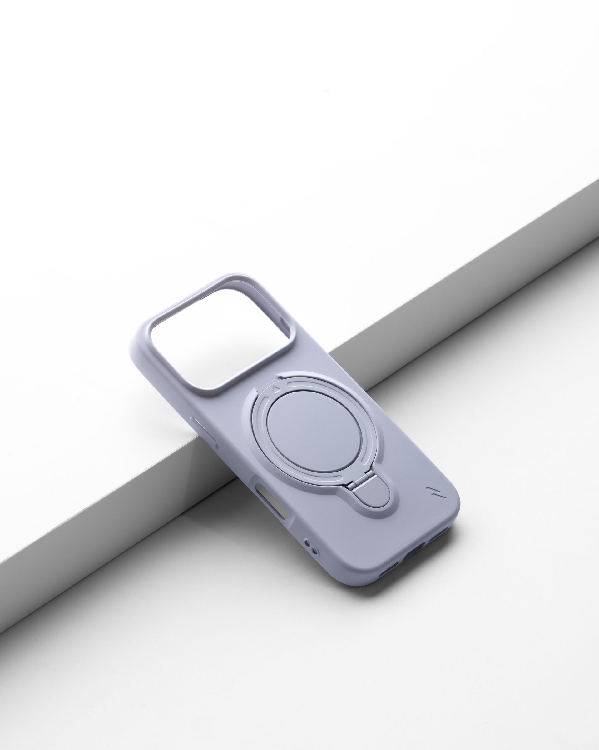 An empty pale lavender ZIZO Revolve case propped at a diagonal against a gray sculptural step