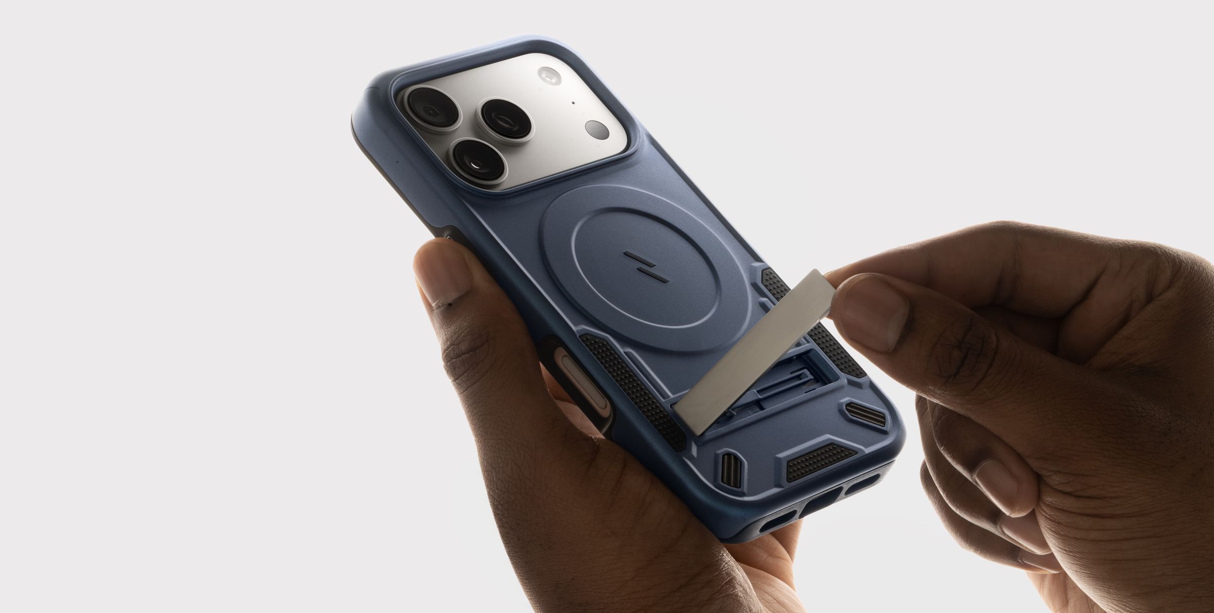 Macro of hands sliding the built-in kickstand out of a blue ZIZO Transform MagSafe case