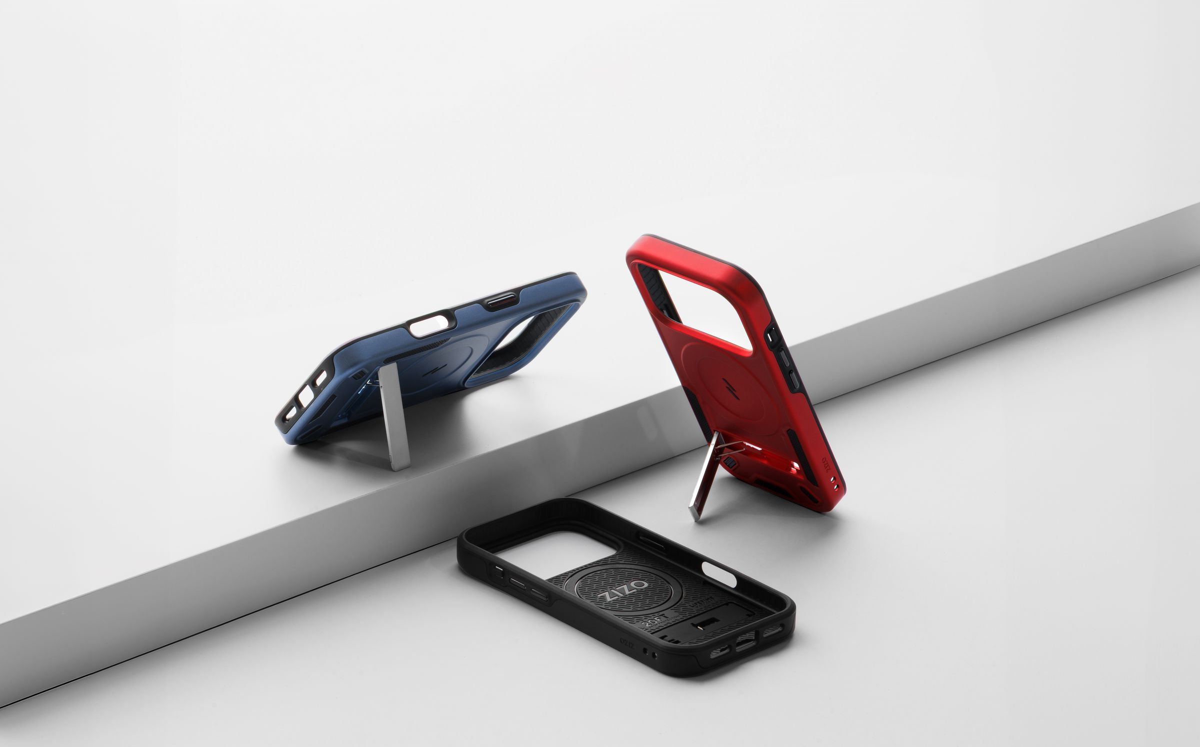 Blue, red and black ZIZO Transform cases propped open on their kickstands along a diagonal gray studio ramp