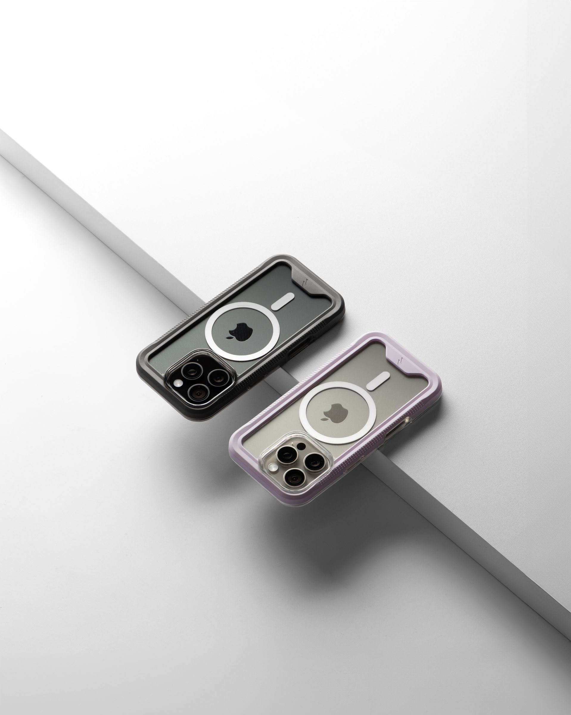 A black-bumper and a purple-bumper ZIZO ION MagSafe case rear-facing on a white ledge with a gray step running diagonally behind them
