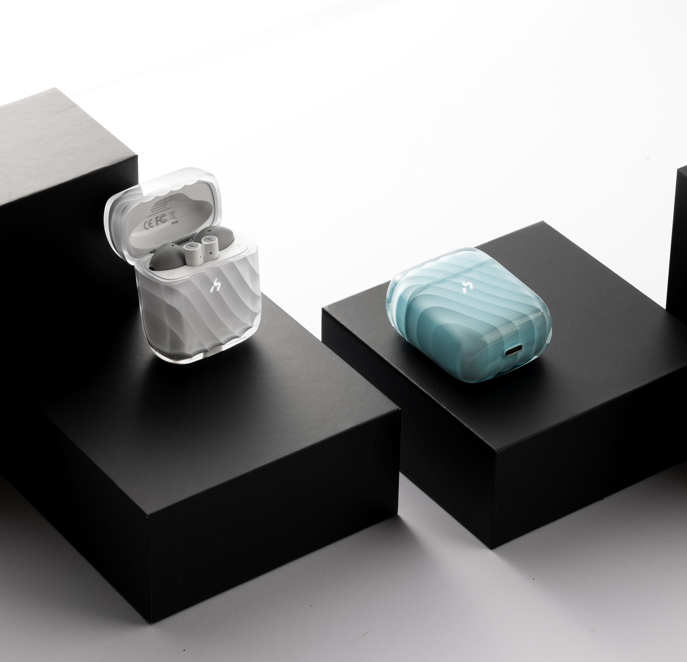 Two ZIZO Halos charging cases, one frosted clear and one pale blue, staged on black plinths