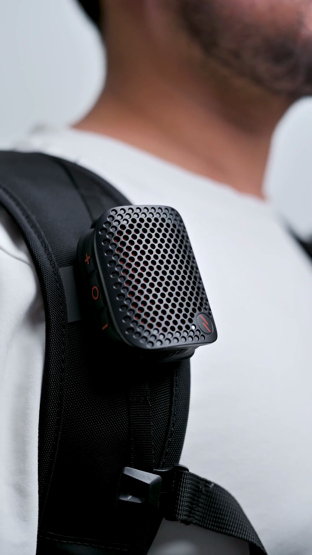 The ZIZO Sonic Clip speaker clipped to a backpack shoulder strap on a person's chest